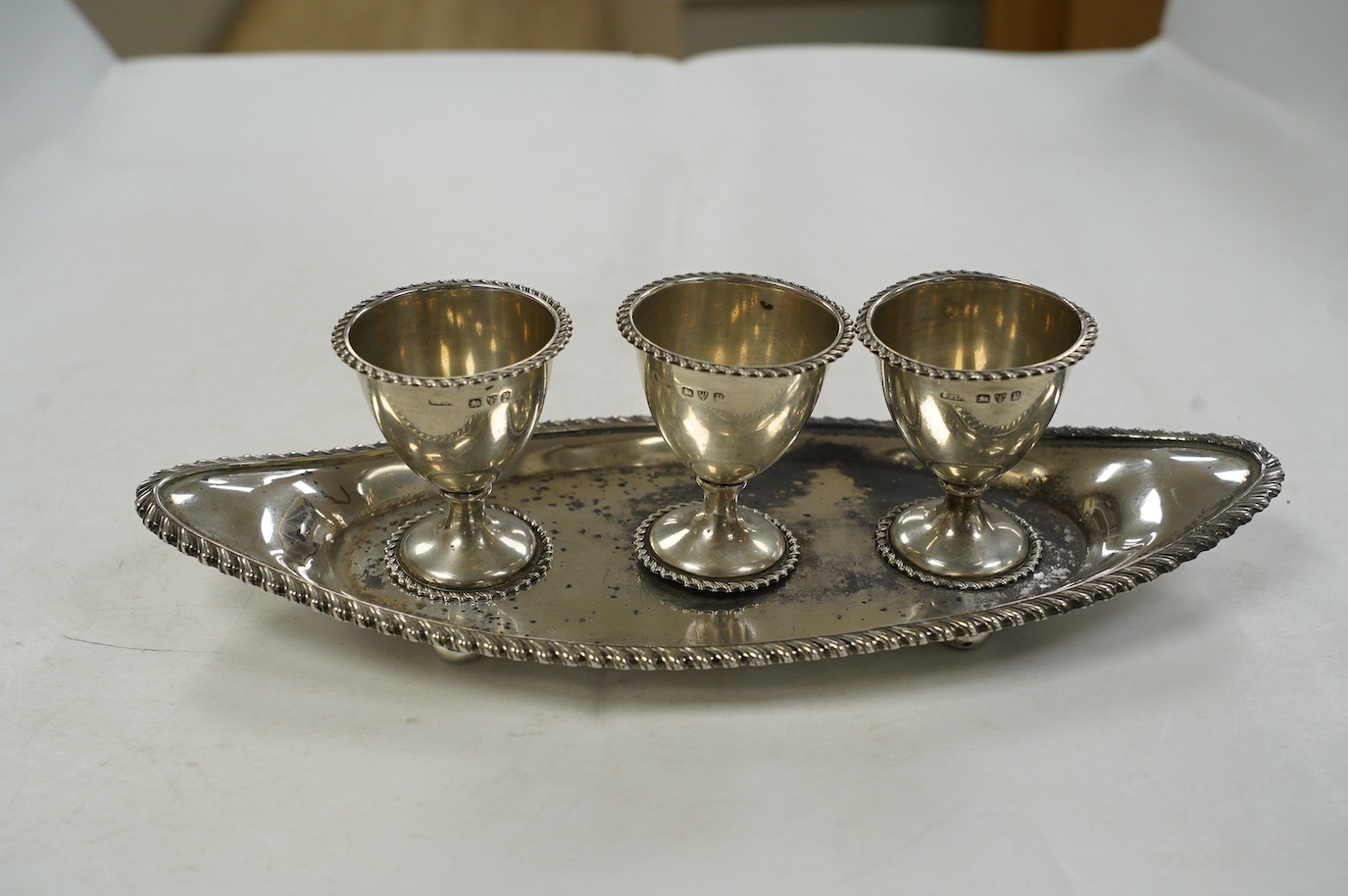 A late Victorian silver egg cruet, with three cups on a navette shaped stand, Chester, 1898, 25.8cm, 10.9oz. Condition - poor to fair